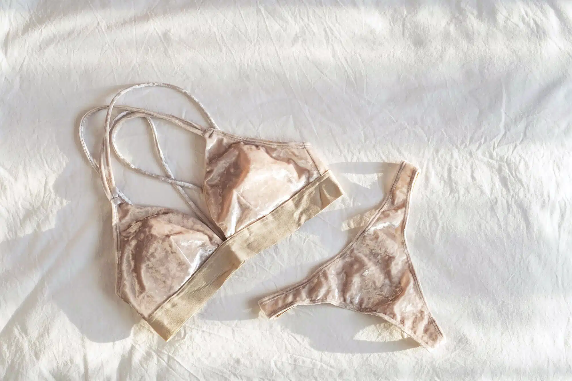 Flat lay of assorted lace bras arranged on white bedsheets.