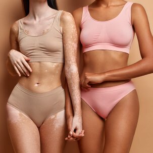 Two models of different skin tones wearing matching nude and blush bra and brief sets, side by side.