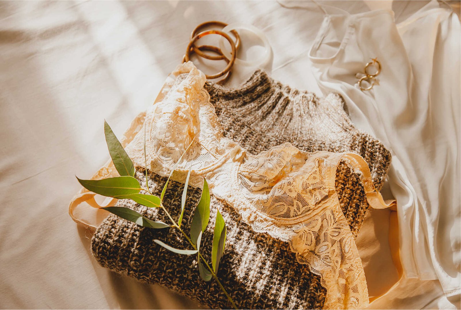 Flat lay of a lace lingerie set styled on a woven straw surface with dried greenery.